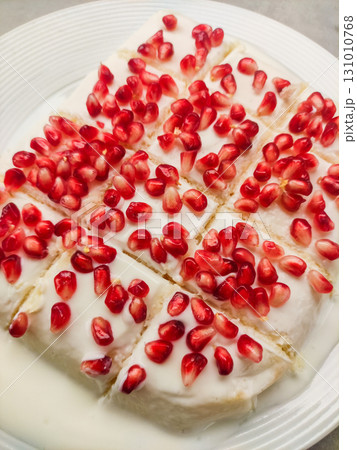 Delicious tres leches milk cake garnished with pomegranate seeds on white plate for birthday 131010768