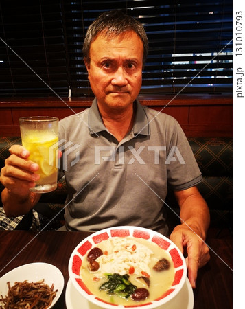 蒸し鶏と棗の薬膳麻辣湯を食べながらレモンハイを飲むシニア男性 131010793