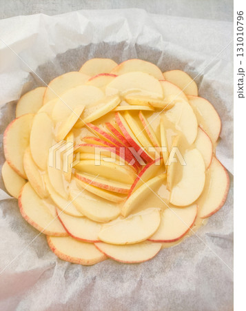 Delicious apple tart with thinly sliced apples baking on parchment paper Delicious apple tart with thinly sliced apples baking on parchment paper 131010796