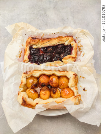 Baking delicious fruit tarts with apricots and plums on parchment paper Baking delicious fruit tarts with apricots and plums on parchment paper 131010798