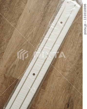 White plastic cable duct for curtains lying on wooden floor in prague 131010896