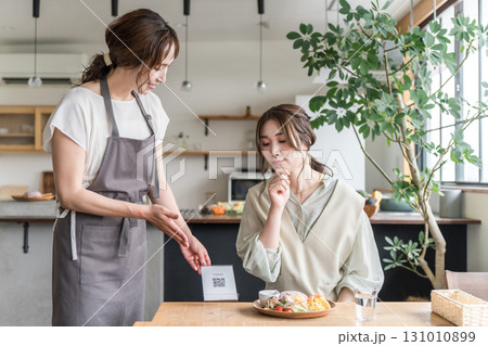 カフェでQRコードを説明,案内する店員と困る,悩む女性客 131010899
