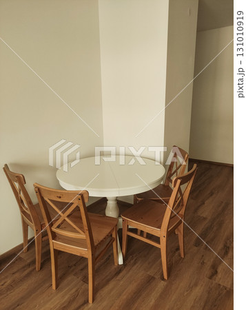 Round white table with four wooden chairs in a corner Round white table with four wooden chairs in a corner 131010919