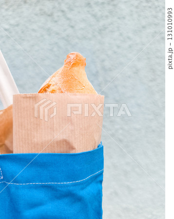 Freshly baked bread in paper bag emerging from blue tote bag in prague Freshly baked bread in paper bag emerging from blue tote bag in prague 131010993