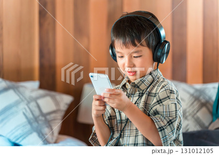 ヘッドホン・ヘッドセットをつけてゲームをする夢中な子供 ヘッドホン・ヘッドセットをつけてゲームをする夢中な子供 131012105