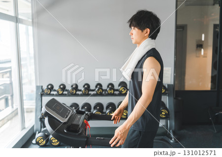 スポーツジムのウォーキングマシンで有酸素運動をする若いアジア人男性 131012571