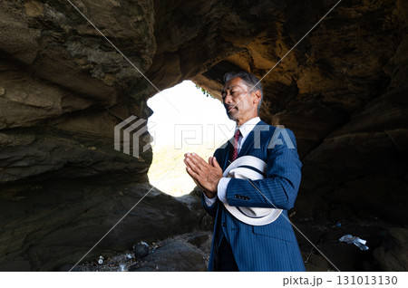 南の島の洞窟で太平洋戦争の慰霊をする遺族のスーツ姿の日本人シニア男性 131013130