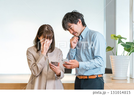 スマートフォンを見て話すビジネスマンとビジネスウーマン(悩む,困る,ストレス,トラブル) スマートフォンを見て話すビジネスマンとビジネスウーマン(悩む,困る,ストレス,トラブル) 131014815