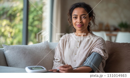 Woman measuring her blood pressure with an electronic monitor at home in natural light Woman measuring her blood pressure with an electronic monitor at home in natural light 131014983