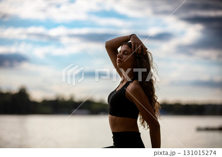 Engaging in a Dynamic Yoga Pose by the tranquil Water, surrounded by natures beauty 131015274