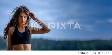 An athletic young woman enjoying herself at the serene lakeside under a clear blue sky 131015277