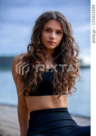 A Young Woman Posing at the Beach Against a Beautiful Sunset Sky, Capturing the Moment 131015289