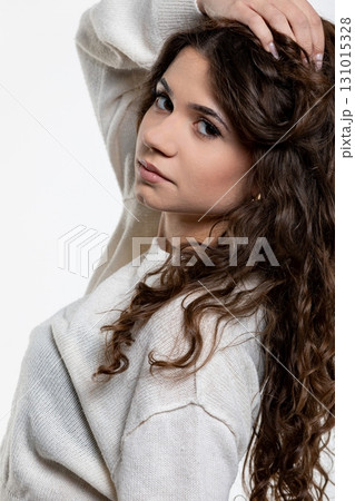An Elegant Young Woman with Beautiful Curly Hair Wearing a Cozy and Stylish Sweater 131015328