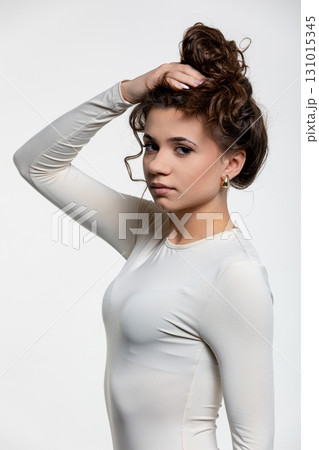 A Young Girl Dressed in a Beautiful White Dress with Curly Hair Posing Elegantly A Young Girl Dressed in a Beautiful White Dress with Curly Hair Posing Elegantly 131015345