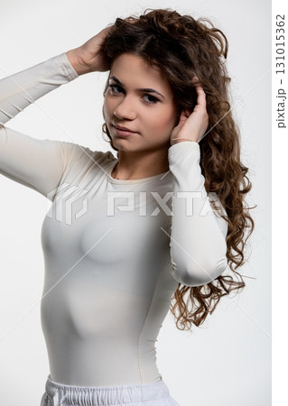 A Stylish Portrait Featuring a Woman with Beautiful Curly Hair Dressed in a Modern Outfit 131015362