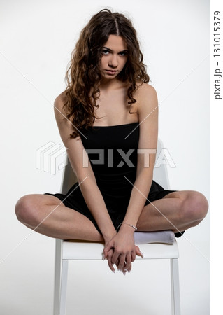 A Fashion Pose Featuring a Stylish Model Elegantly Sitting on a Chair in a Studio Environment A Fashion Pose Featuring a Stylish Model Elegantly Sitting on a Chair in a Studio Environment 131015379