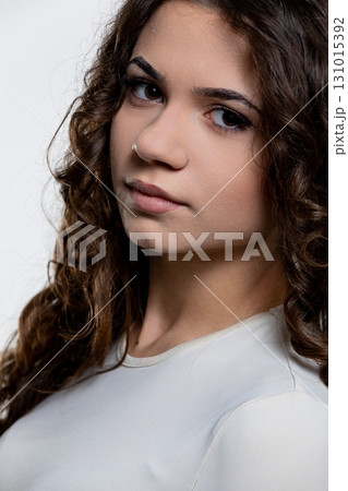 A captivating portrait of a young woman with curly hair, set in soft lighting enhancing her charm 131015392
