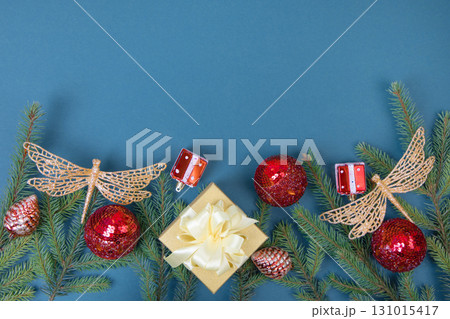 Christmas dark blue background with green Christmas tree branches and red decorative balls, golden dragonflies and gift box with space for greetings, suggestions, labels, and your design. Flat lay 131015417