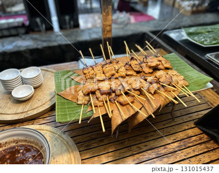 Grilled meat skewers served on banana leaf with dipping sauce Grilled meat skewers served on banana leaf with dipping sauce 131015437