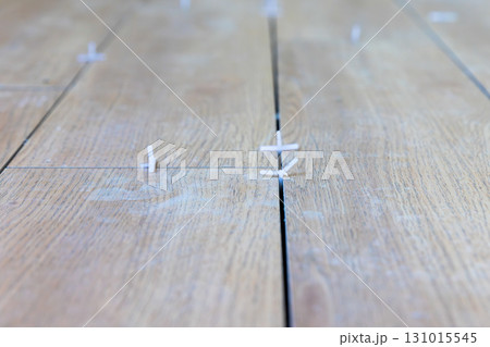 Worker use plastic tile spacers for accurate alignment of floor tiles, Semi-dry floor screed. 131015545