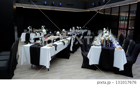 Refined dining setup featuring pristine white draped tables, dark accents creating sophisticated ambiance within contemporary restaurant interior design 131017676