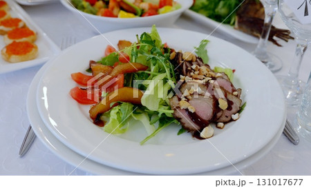 Seared duck breast resting on crisp arugula, accompanied by caramelized pears, ripe tomatoes, and glossy balsamic reduction, highlighting gourmet flavor profiles 131017677