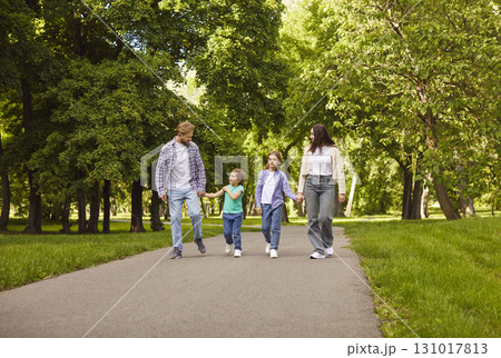 Happy parents mother, father with two children having a walk in the park together. Happy parents mother, father with two children having a walk in the park together. 131017813