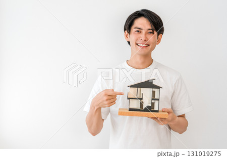 住宅模型を持つ笑顔の若いアジア人男性（マイホーム,一戸建て,家づくり） 131019275