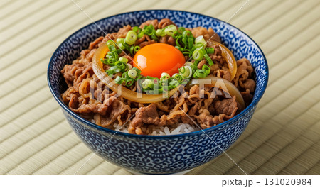 Gyudon with Raw Egg Yolk, Onion, and Green Onion in Blue Ceramic Bowl 131020984