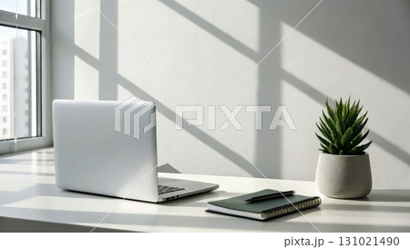 Modern workspace with laptop, notebook, and plant showcasing minimalism and productivity 131021490