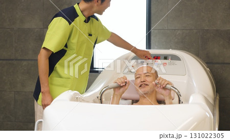 機械浴で入浴介助を受けるアジア人高齢者 機械浴で入浴介助を受けるアジア人高齢者 131022305