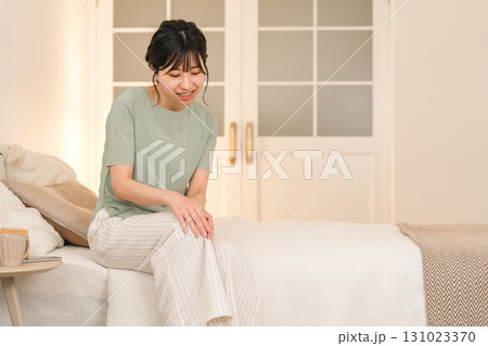 夜のベッドルームで膝を痛がる若いアジア人女性 131023370