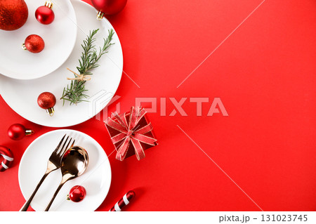 White dishes with Christmas ornaments on red background. White dishes with Christmas ornaments on red background. 131023745