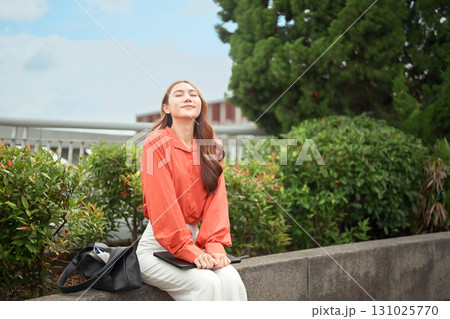 A female office worker relaxing and breathing fresh air on the rooftop of an office building during her break 131025770