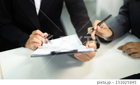 Closeup business two colleague consulting with document and laptop Closeup business two colleague consulting with document and laptop 131025845