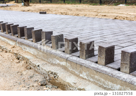 Newly Laid Paving Stones on a Developing Pedestrian Pathway in a Park, Showcasing Modern Urban Design and Natural Surroundings Newly Laid Paving Stones on a Developing Pedestrian Pathway in a Park, Showcasing Modern Urban Design and Natural Surroundings 131027558