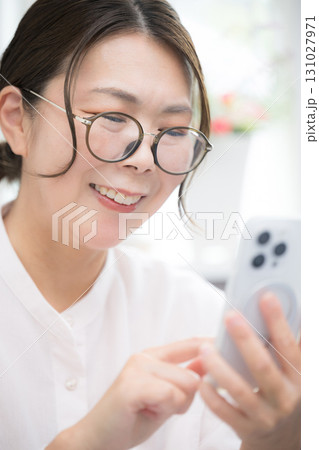 部屋でスマホをタップする40代の女性上半身のクローズアップ	 131027971