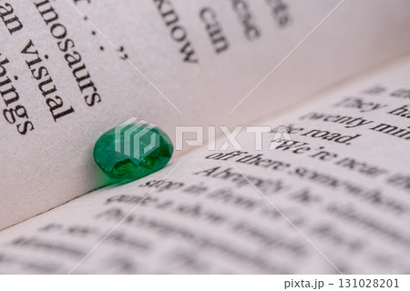 A green gemstone is on a page of a book A green gemstone is on a page of a book 131028201