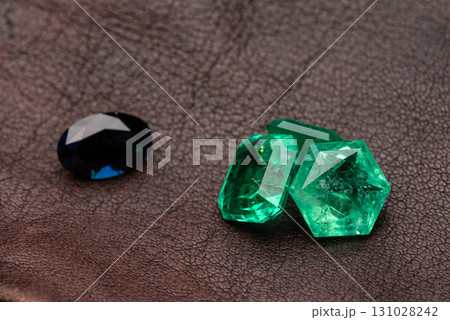 Three green gems are on a brown surface Three green gems are on a brown surface 131028242