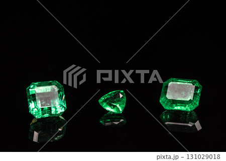 Three green gemstones are displayed on a black background 131029018