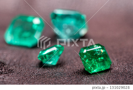 Four green gemstones are displayed on a dark surface 131029028