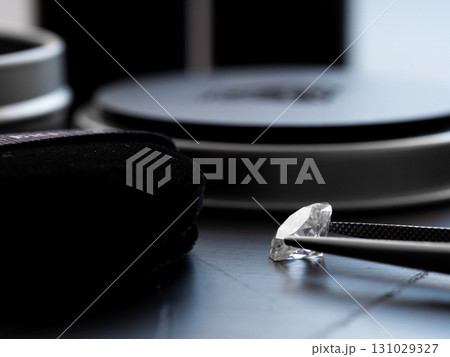 A diamond is on a table next to a magnifying glass 131029327