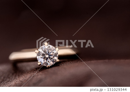 A diamond ring is sitting on a brown surface 131029344