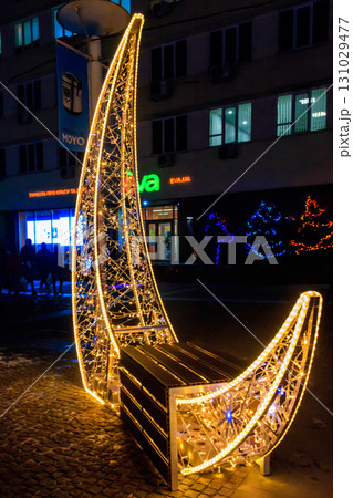Illuminated crescent shaped bench in a park. Christmas urban decoration 131029477