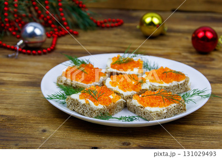 Canapes with red caviar and Christmas decorations on wooden table 131029493