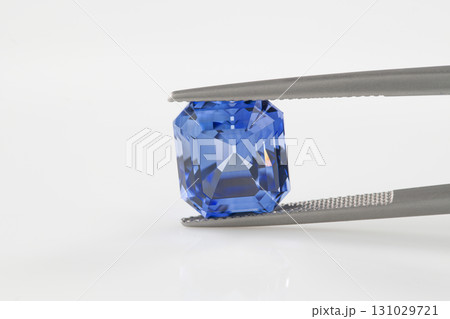 A blue gemstone is being held up by a metal tool A blue gemstone is being held up by a metal tool 131029721
