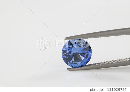 A blue diamond is being held up by a metal tool 131029725