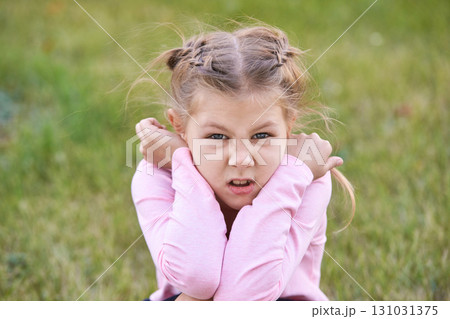 Caucasian girl child with braided hair showing defiant expression in pink shirt Caucasian girl child with braided hair showing defiant expression in pink shirt 131031375