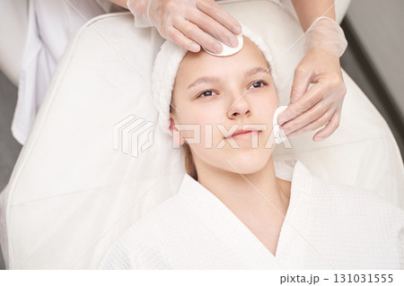 Young caucasian female enjoying facial treatment at spa with relaxing skincare Young caucasian female enjoying facial treatment at spa with relaxing skincare 131031555