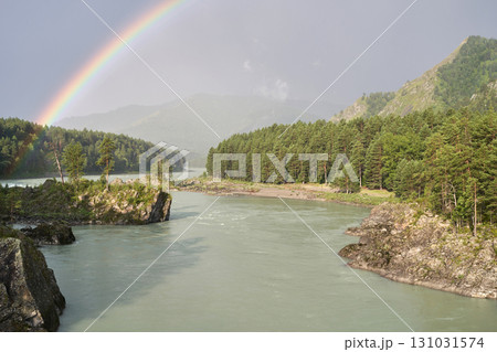 Scenic river with rainbow and forested mountains under a clear sky Scenic river with rainbow and forested mountains under a clear sky 131031574